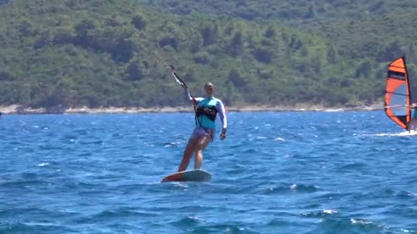 Κατάλληλο θηλυκό τουρίστα που επισκέπτεται κροατική ακτή kitefoils κατά μήκος της ήρεμης Αδριατικής θάλασσας — Αρχείο Βίντεο