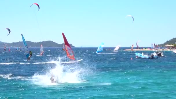 Turysta wpada do wody morskiej podczas jazdy na falach z innymi windsurferami. — Wideo stockowe