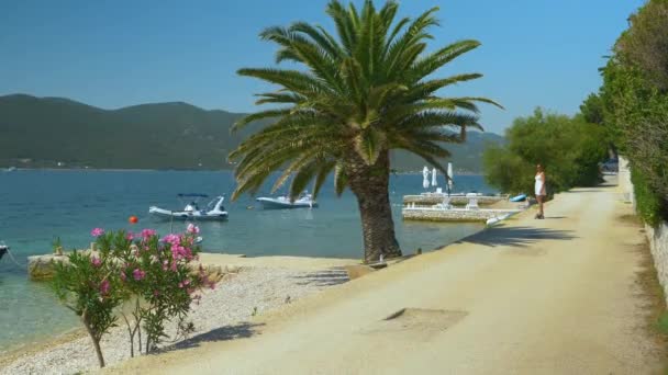 Femme en robe de soleil fait du skateboard électrique le long d'une route côtière en Croatie — Video