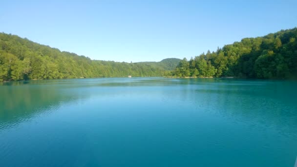 AERIAL: Latanie nad spokojnym głębokim błękitnym jeziorem w Plitwicach i w kierunku łodzi wycieczkowej. — Wideo stockowe
