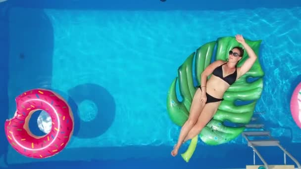 TOP DOWN: Młoda biała kobieta leży na wielkiej platformie liści w basenie domowym. — Wideo stockowe