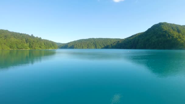 AERIAL: repül át a nyugodt mély kék tó Plitvice egy napos nyári napon. — Stock videók