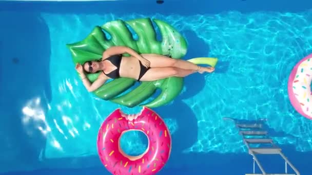 VERTICAL: Mulher despreocupada desfruta de um dia ensolarado de verão em sua piscina de jardim azul. — Vídeo de Stock