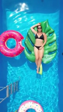 Güneşli bir hafta sonunda bikinili bir kadın bahçe havuzunda dinleniyor..