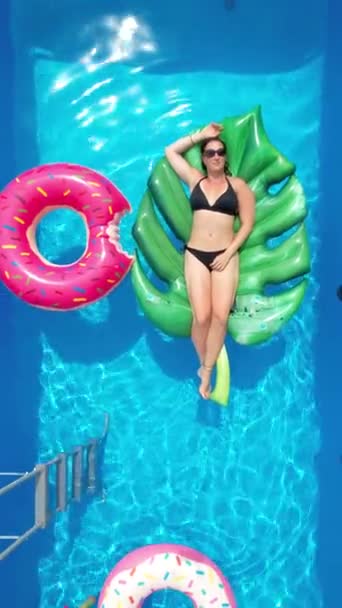 VERTICAL: Vrouw in een bikini ontspant in haar tuin zwembad op een zonnig weekend. — Stockvideo