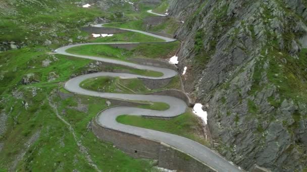 AERIAL: Vista aérea de uma estrada de grampo de cabelo snaking até uma montanha na Suíça. — Vídeo de Stock