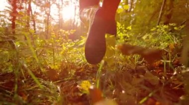 Lastik bot giyen bir kadın sonbaharda renk değiştirerek ormanda koşar..