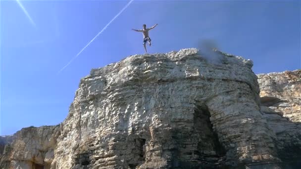 El hombre salta de un acantilado del océano — Vídeo de stock