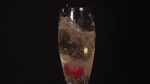 Клубника падает в шампанское — стоковое видео