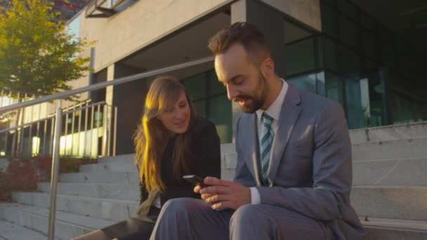 Empresário mostrando conteúdo no smartphone para empresária — Vídeo de Stock