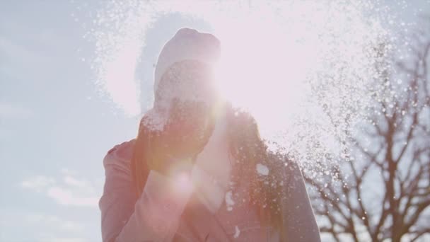 Woman blows snowflakes in sunny winter — Stock Video