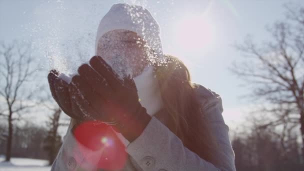 Kvinna blåser snöflingor över solen — Stockvideo