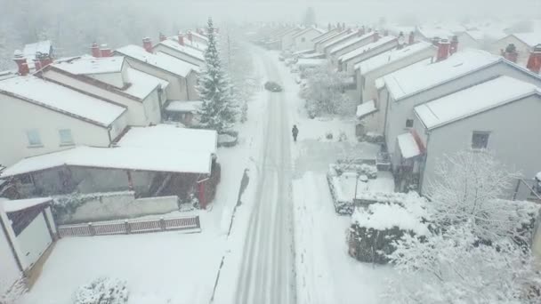 Человек, идущий через пригород в снежную бурю — стоковое видео