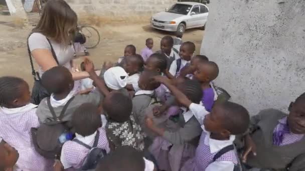 Kaukasisk kvinna ger godis till afrikanska barn — Stockvideo