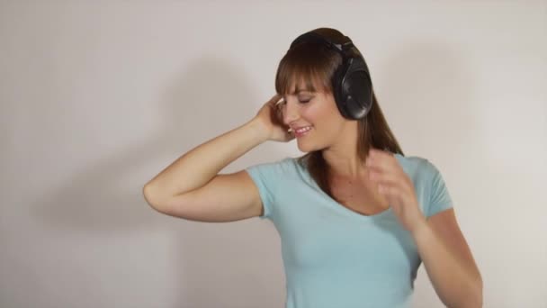 Молодая брюнетка слушает музыку в наушниках — стоковое видео