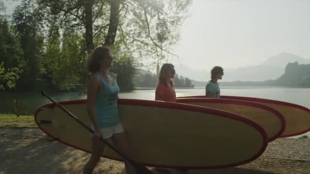 SLOW MOTION: Girl friends with stand up paddle boards walking to the lake — Stock Video