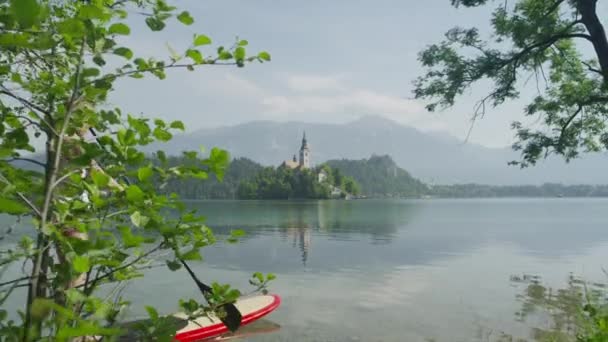 LOW MOTION: Casal levante-se remar com placas SUP no belo lago Bled — Vídeo de Stock