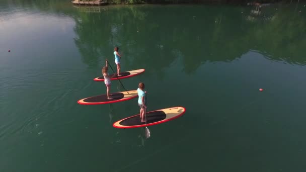 AERIAL: Voando acima surfista namoradas SUP embarque no lago Bled na bela manhã — Vídeo de Stock