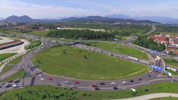 空中:車でいっぱいの大きな高速道路のラウンドアバウト交差点の周りを飛ぶ — ストック動画