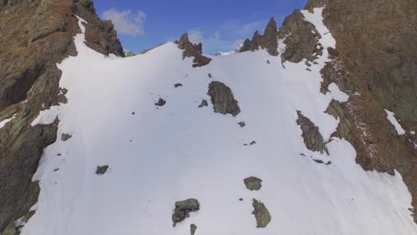 Aerial: vliegen over de nok van de besneeuwde bergen — Stockvideo