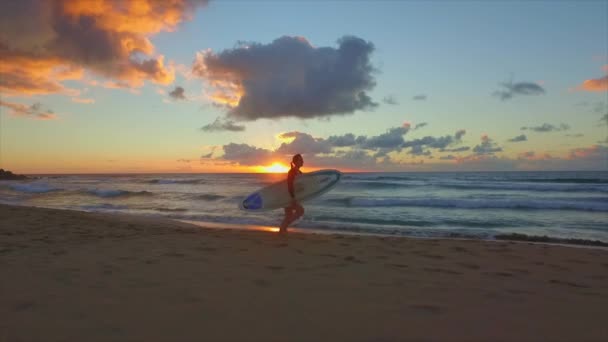 沿着沙滩跑在日落时的慢动作: 年轻冲浪者女人 — 图库视频影像