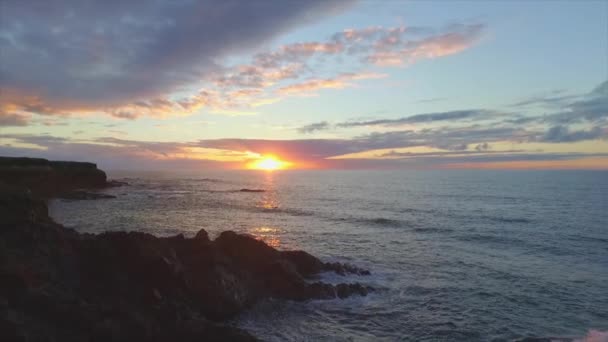 Luchtfoto Slow Motion: oceaan golven slaan rotsachtige kust bij zonsondergang — Stockvideo