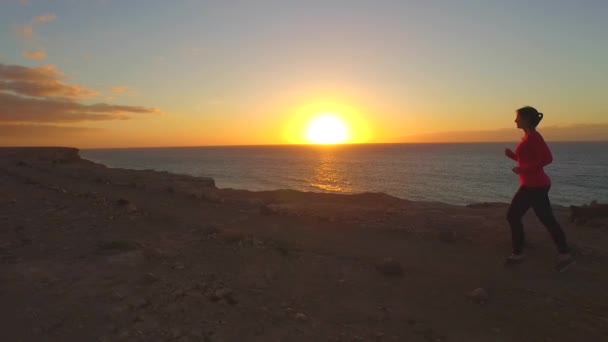 AERIAL SLOW MOTION: Woman jogging on top of ocean cliff — Stock Video