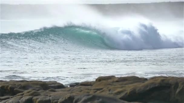 Zeitlupe: Schöne Welle rollt auf die felsige Küste zu — Stockvideo