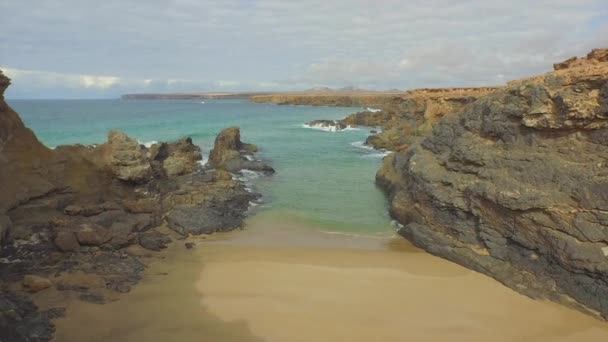 AERIAL: Volando sobre una hermosa playa de arena escondida en altos acantilados — Vídeo de stock