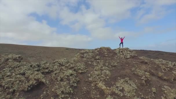 Antenne: Frau steht mit erhobenen Händen auf Vulkankrater — Stockvideo