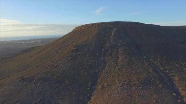 AERIAL: Volando sobre la mujer alegre en la cima de la montaña volcánica — Vídeo de stock