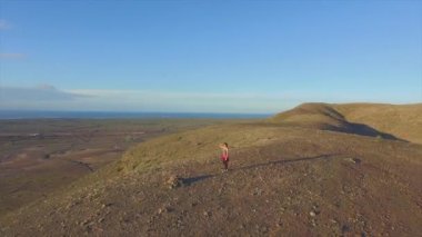 Anten: Dağın tepesinde el kaldıran neşeli kadın