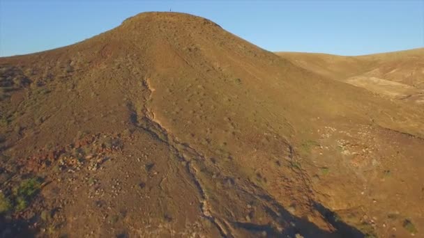 AERIAL: Mujer joven levantando las manos en la cima de la montaña volcánica — Vídeo de stock