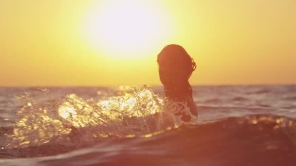 Ağır çekim: deniz suyu ile güzel günbatımında oynayan kadın — Stok video