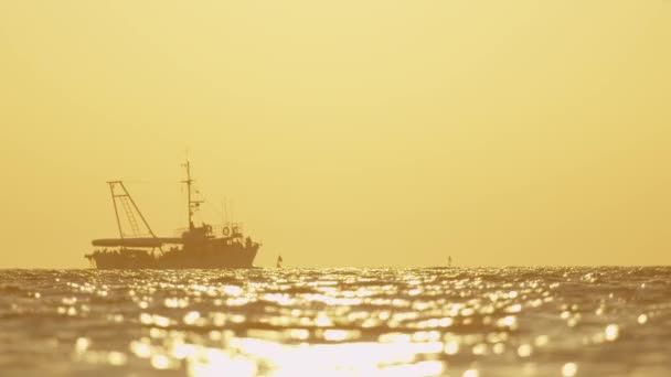 LOW MOTION: Barco de pesca navegando no horizonte do oceano ao pôr do sol — Vídeo de Stock