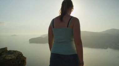 Kadın ayakta kollarını yükselterek uçurumun tepesinde