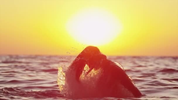 MOTION LENT : Femme jetant l'eau de l'océan au-dessus du soleil couchant — Video