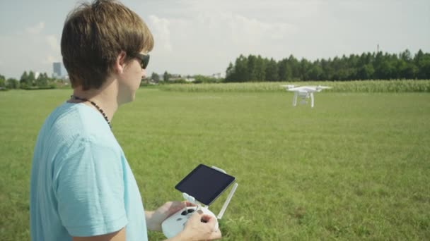 LOW MOTION: Piloto jovem voando pequeno drone amador com transmissor — Vídeo de Stock