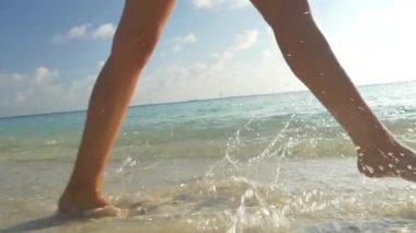 Ağır çekim portre: sığ suda kum plajındaki yürüyüş