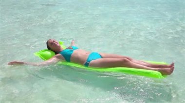 Yavaş Hareket: Şişme hava yatağı şiltesinde bronzlaşmaya devam eden mutlu kadın güneş