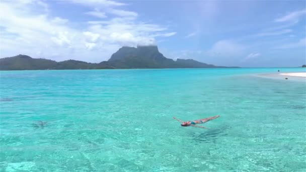 MOVIMIENTO Lento: Mujer relajada nadando en perfecta laguna de Bora Bora — Vídeo de stock