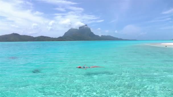 Щаслива молода жінка плаває в екзотичній блакитній лагуні — стокове відео