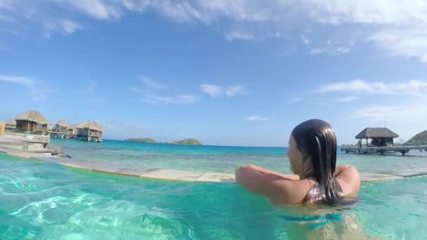 Жінка в басейні насолоджується видом на розкішний курорт — стокове відео