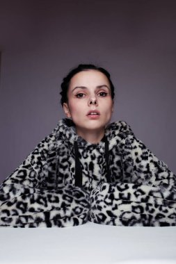 Kapüşonlu, açık renk arka planlı bir kadın.