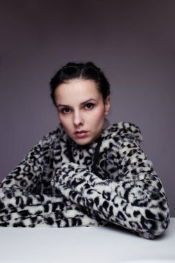 Kapüşonlu, açık renk arka planlı bir kadın.