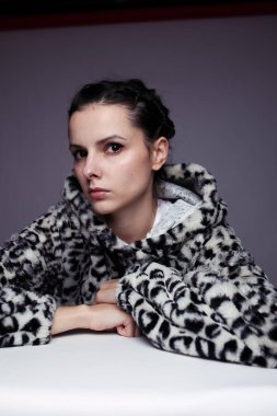 Kapüşonlu, açık renk arka planlı bir kadın.