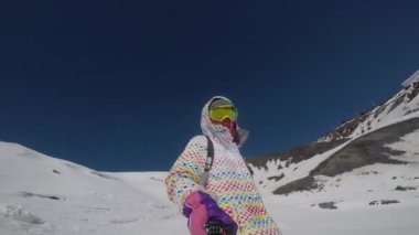 Kız dağdan snowboard yapıyor.