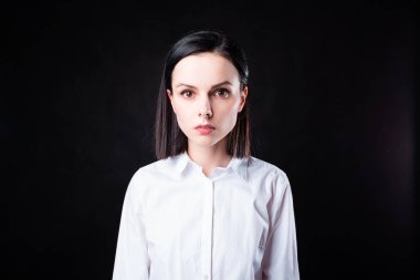 Siyah arka planda beyaz gömlekli kadın.