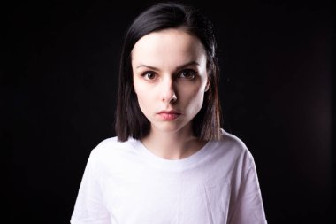 Siyah arka planda beyaz tişörtlü kadın.