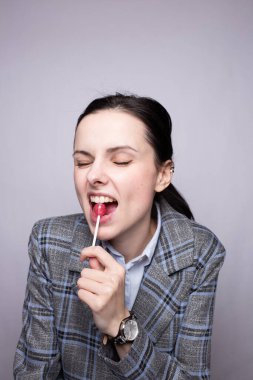 Lolipop yiyen iş kadını, gri arka plan